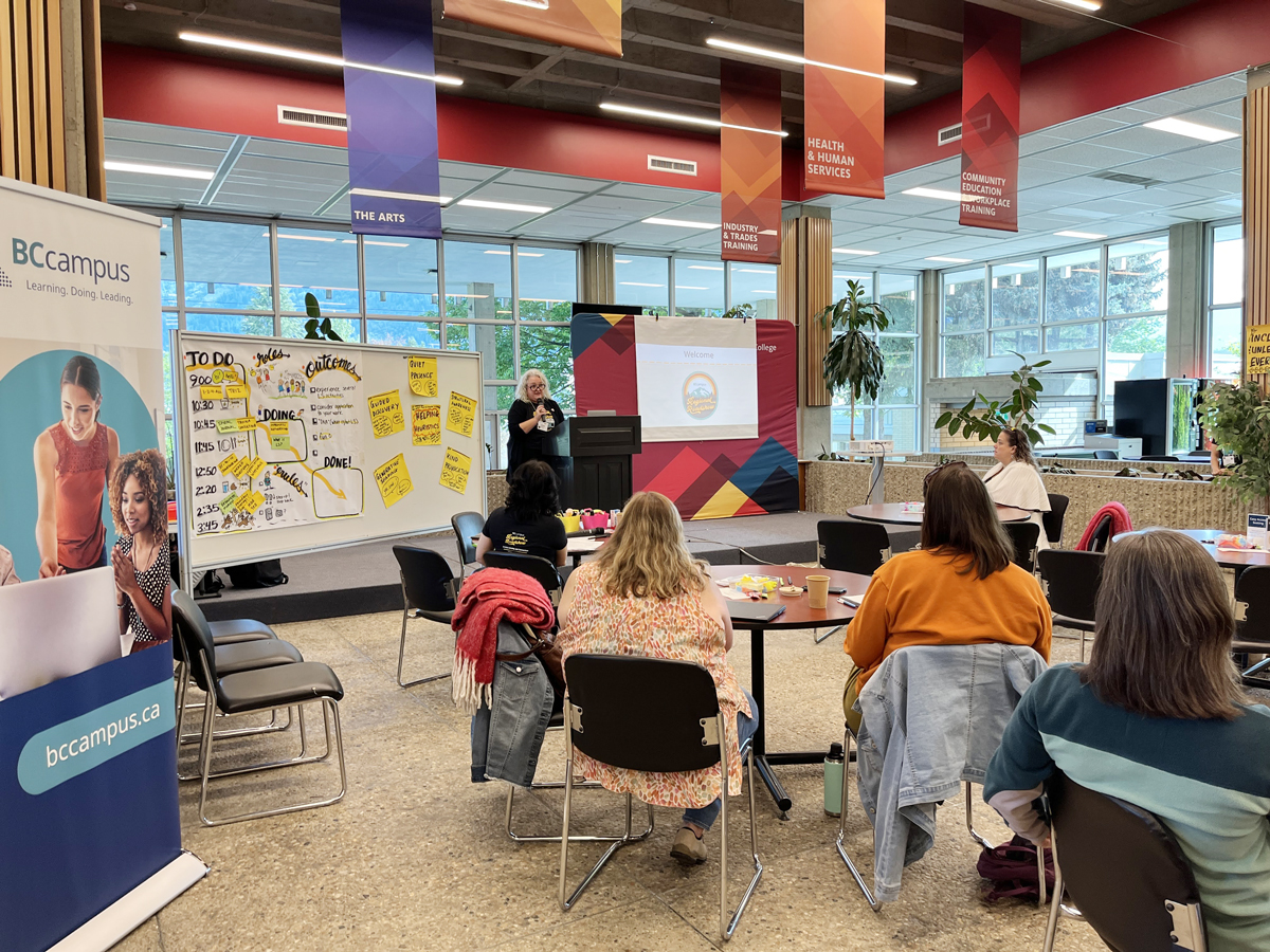 Tracy from BCcampus presents to a room of people. The room has big windows and the BCcampus banner is visible in the foreground.